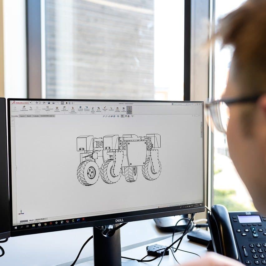 Ingénieur Concipi travaillant sur un assemblage 3D dans SolidWorks : châssis et roues d'une machine agricole.